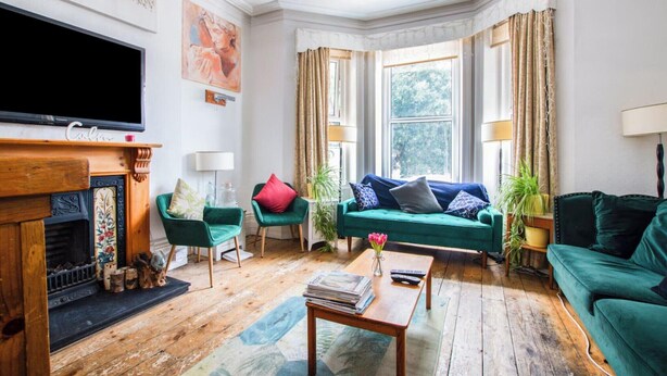 A cozy living room with a fireplace, green sofas, a coffee table, and a television.