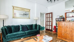 Ein Wohnzimmer mit einem grünen Sofa, einem Holztisch, einem Bücherregal und einem Spiegel.
