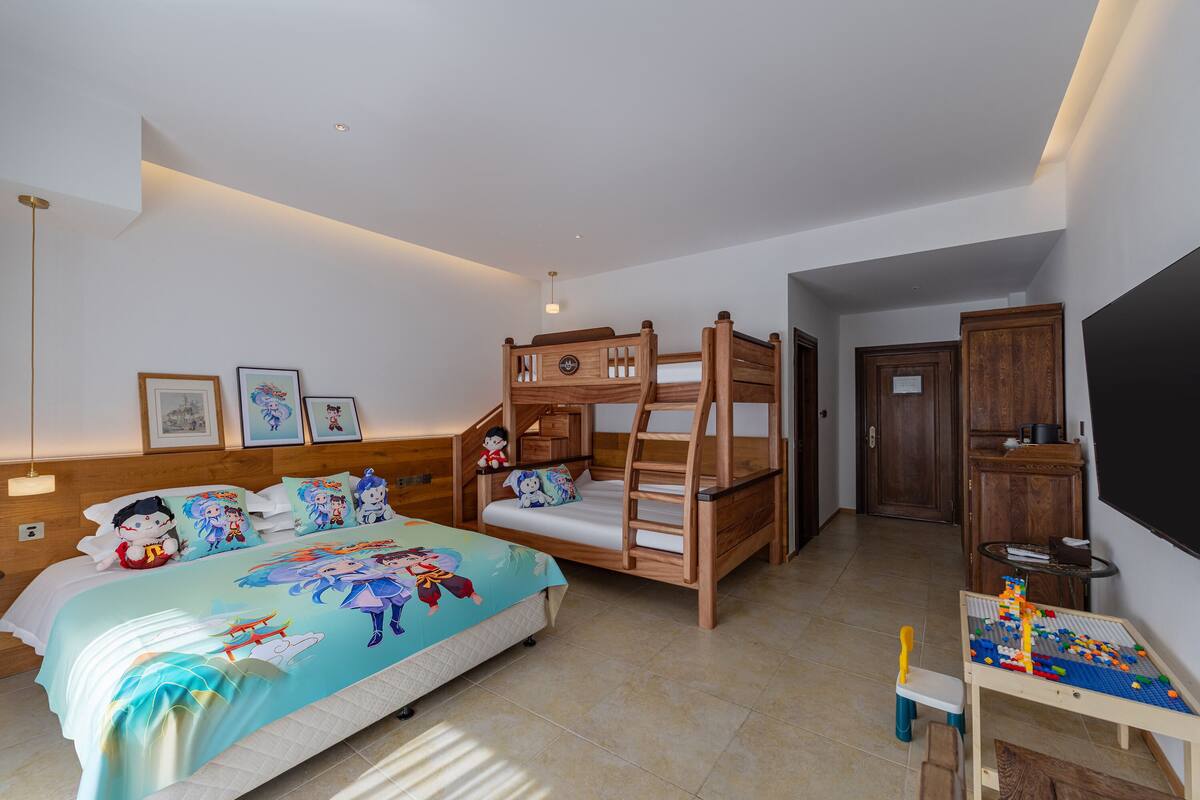 Ein Schlafzimmer mit einem Etagenbett, einem Schreibtisch mit einem Spielzeug und einem Bett mit einer farbenfrohen Tagesdecke.