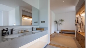 Un baño moderno con dos lavamanos, un espejo grande y un banco de madera.