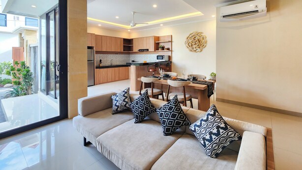A modern living room with a sofa, dining table, and kitchen in the background. - Enjoyable Ayur Villa in beautiful Bali (Bali)