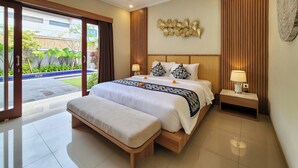 A modern bedroom with a large bed, a bench, and a view of a garden through a sliding door. - Enjoyable Ayur Villa in beautiful Bali (Bali)