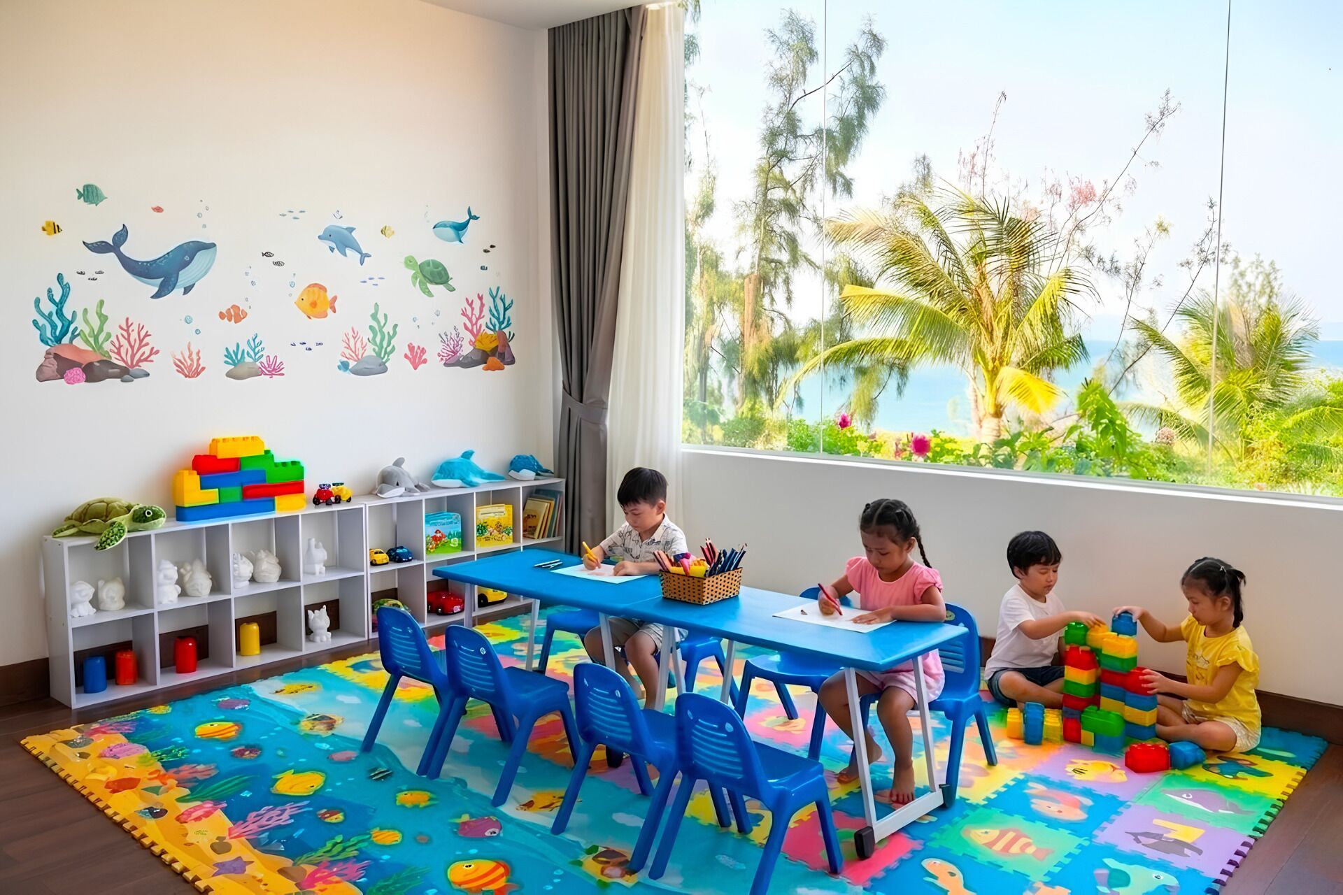 Una sala de juegos para niños con un ventanal grande, alfombras de juego coloridas y un muro decorado con vida marina.