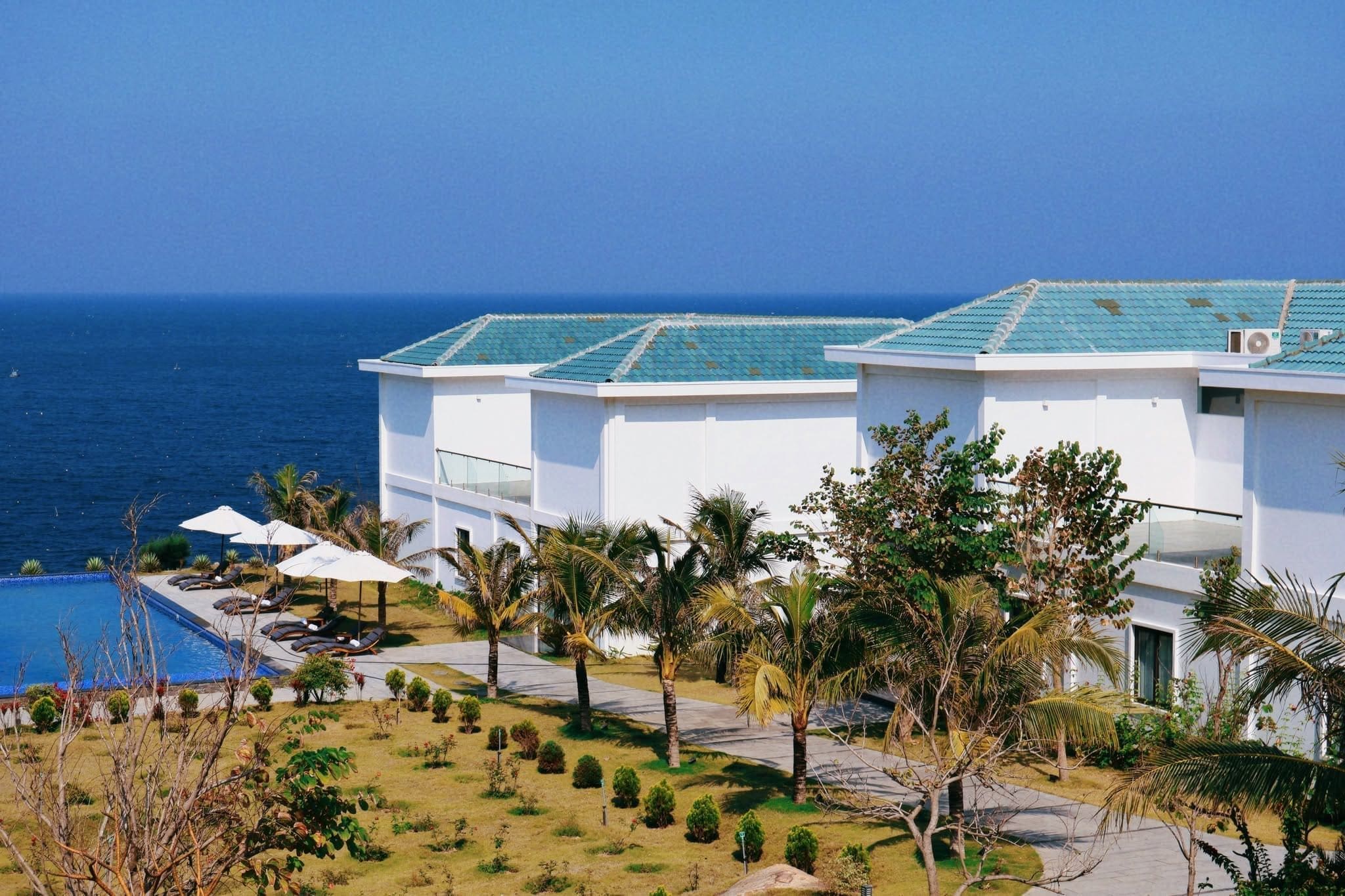 A resort with a pool, palm trees, and a view of the ocean.