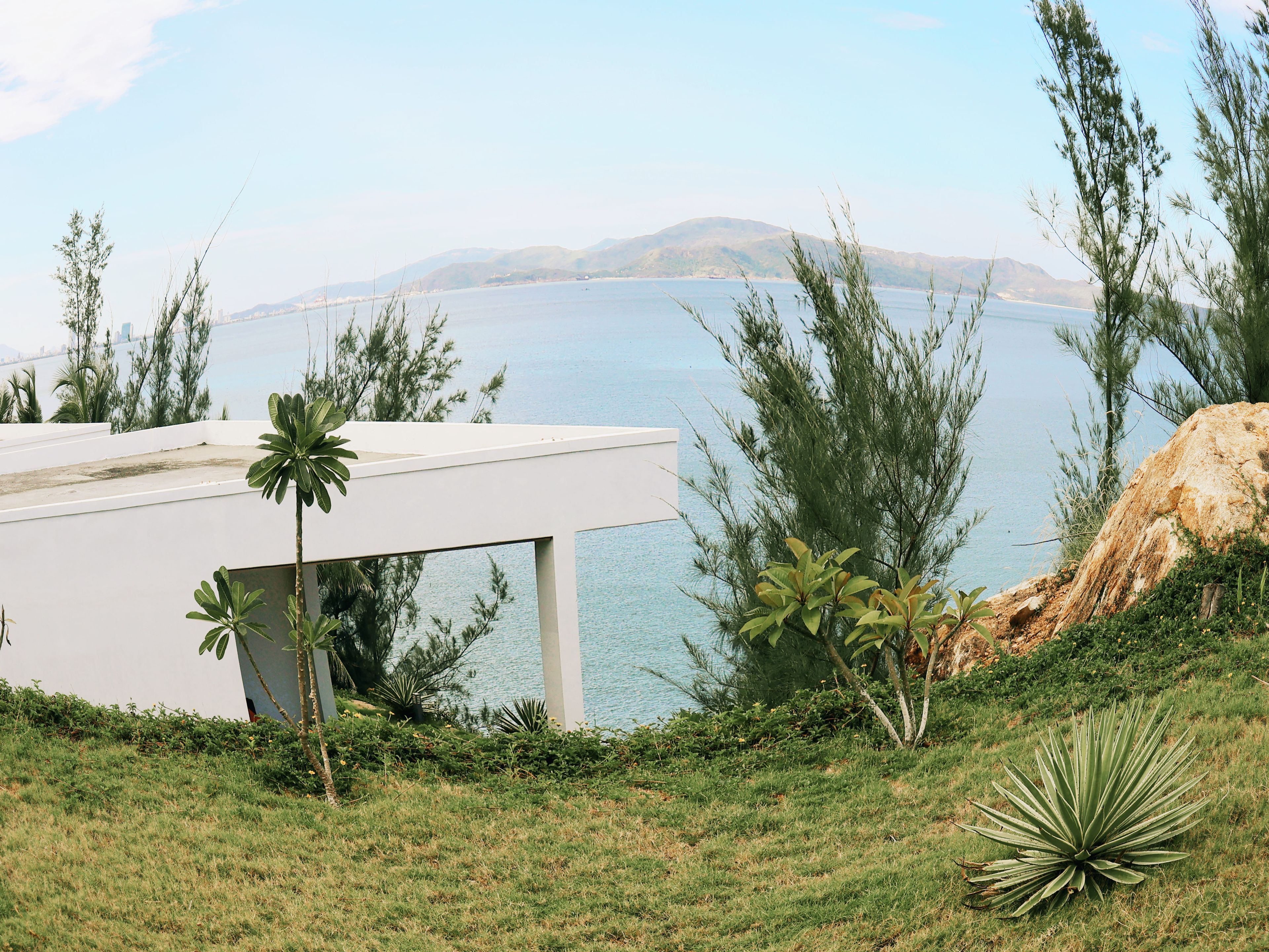 A modern building with a flat roof overlooking a body of water and distant hills.