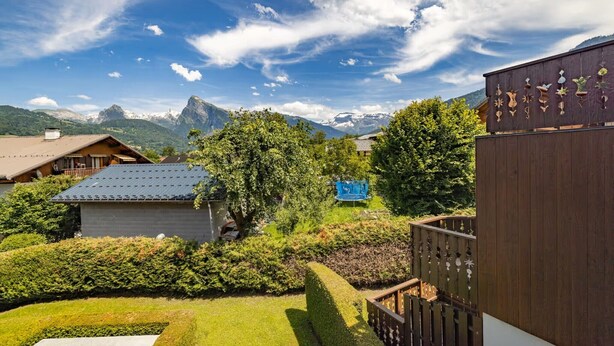A mountain lodge with a view of snow-capped peaks, surrounded by lush greenery and a well-maintained garden. - Apartment in heart of Morillon Village (Morillon)