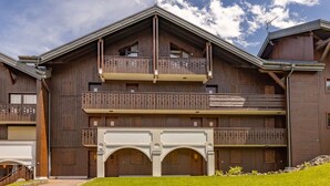 A two-story wooden building with balconies, a covered entrance, and a clear sky. - Apartment in heart of Morillon Village (Morillon)