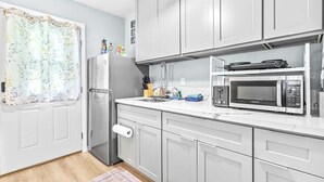Eine moderne Küche mit grauen Schränken, einem Edelstahl-Kühlschrank, einer Mikrowelle und Küchenpapier.