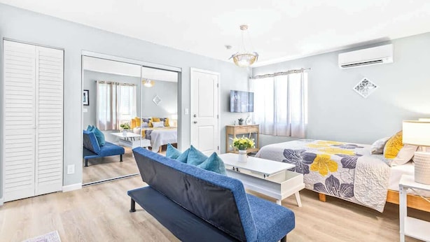 Ein modernes Schlafzimmer mit Bett, Sofa, Schreibtisch und Kleiderschrank.