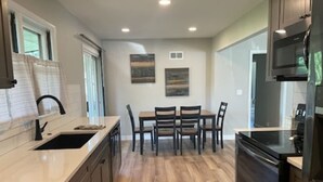 A kitchen with a central island, a dining table with chairs, a built-in oven, and a microwave. - Sleeps 10, Available Garage! (Sturgis)