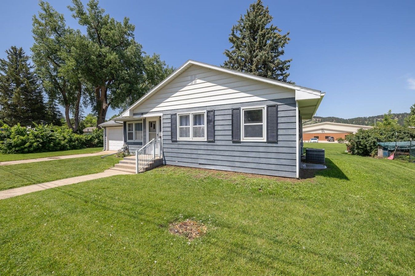 A single-story house with a front porch, a small staircase, and a well-maintained lawn.