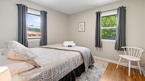 A bedroom with a bed, a chair, a window, and a picture on the wall. - Sleeps 10, Available Garage! (Sturgis)