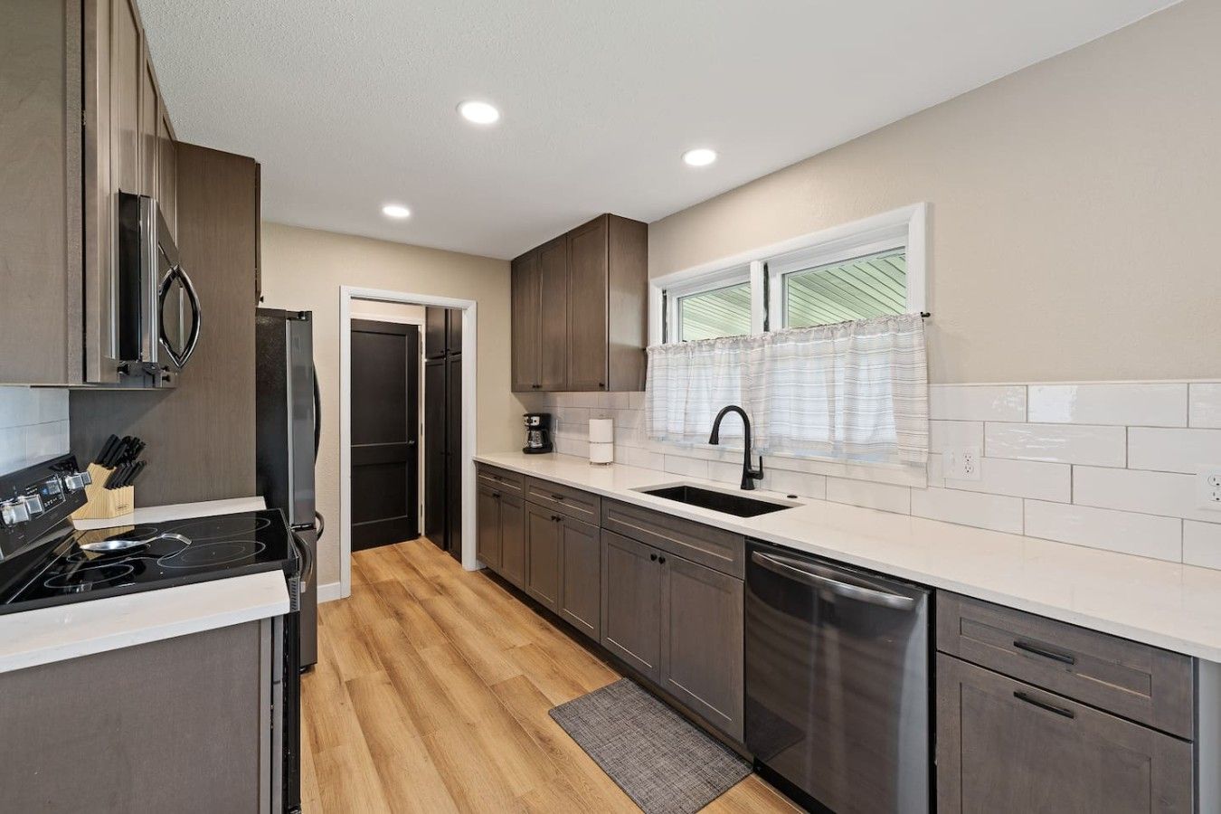 A modern kitchen with a built-in stove, a dishwasher, and a window with a view.