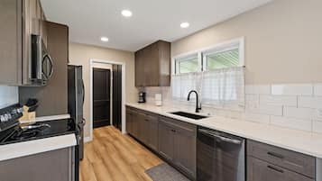A modern kitchen with a built-in stove, a dishwasher, and a window with a view.
