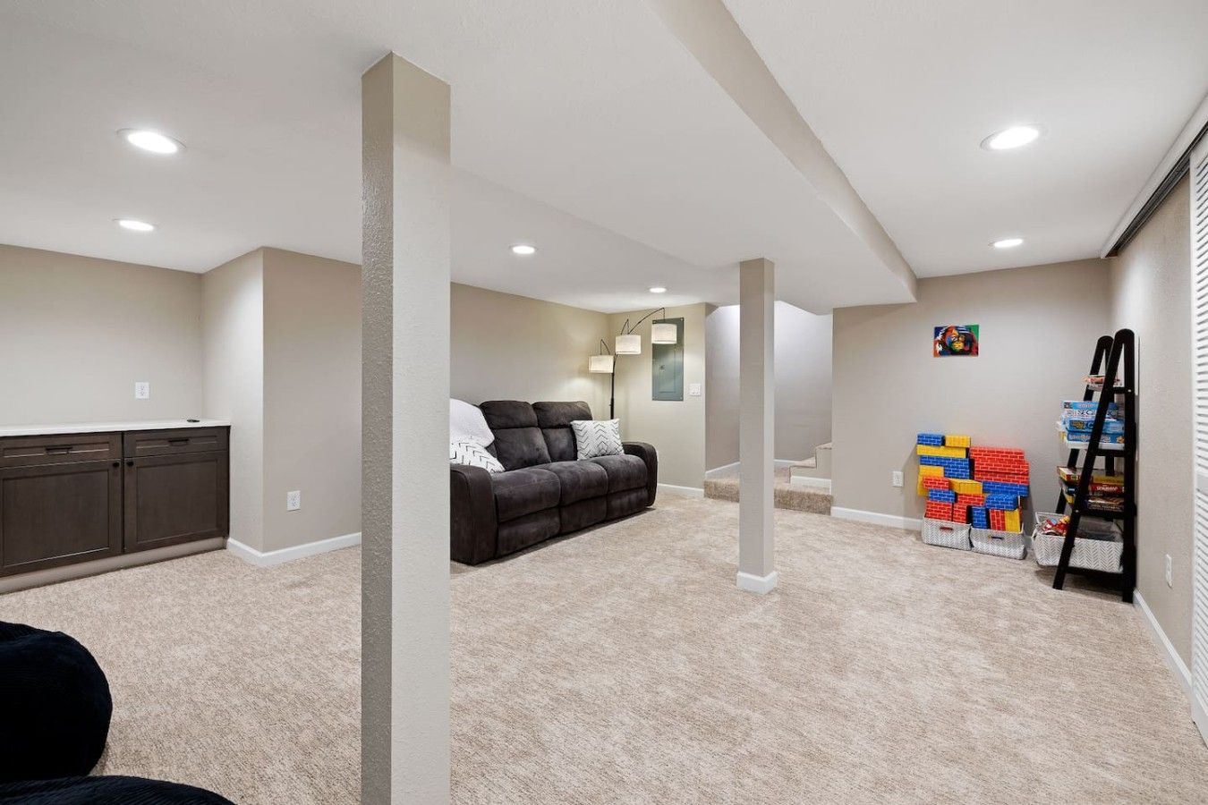 A home interior with a dark brown sofa, a white wall-mounted shelf, and a stack of colorful building blocks.