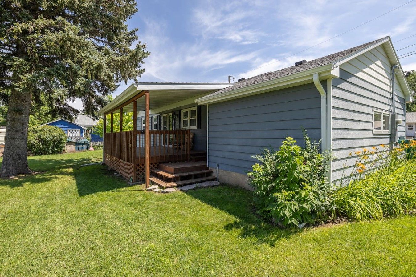 A single-story house with a covered porch, a front yard, and a small garden.