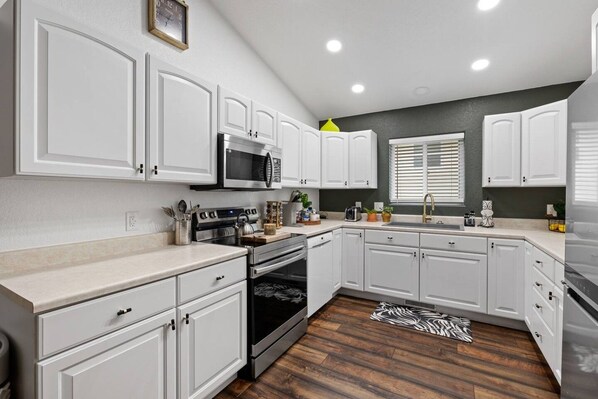 A modern kitchen with white cabinetry, stainless steel appliances, and a zebra-patterned rug.