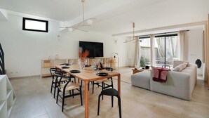 Una sala de estar moderna con comedor, televisor de pantalla plana y sofá.