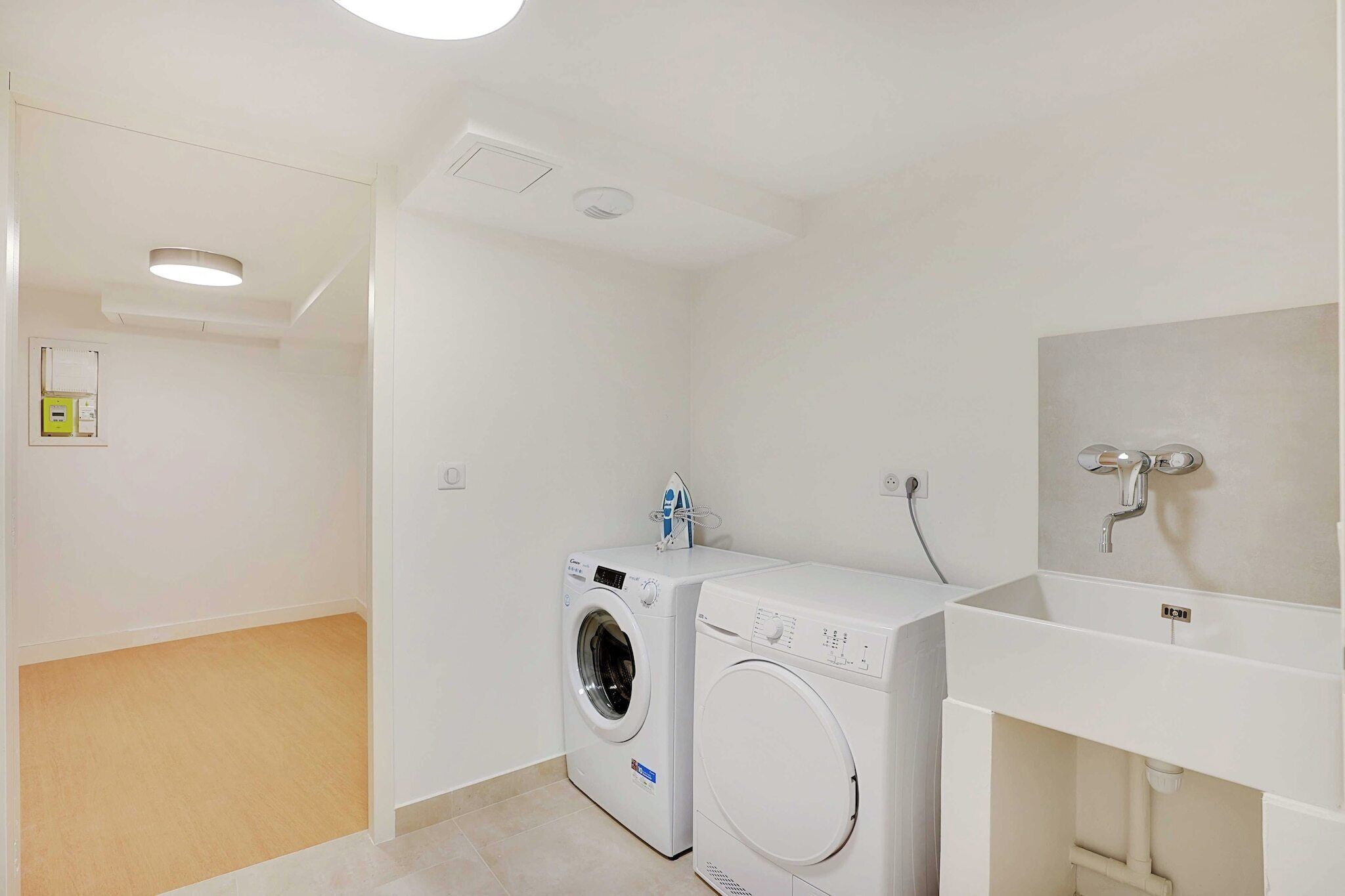 A laundry room with two washing machines and a sink.