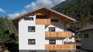 Ein mehrgeschossiges Gebäude mit hölzernen Balkonen, einem geneigten Dach und einer Bergkulisse.