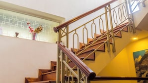 A staircase with wooden steps and metal railings, a window with a decorative vase, and a wall with a framed picture.