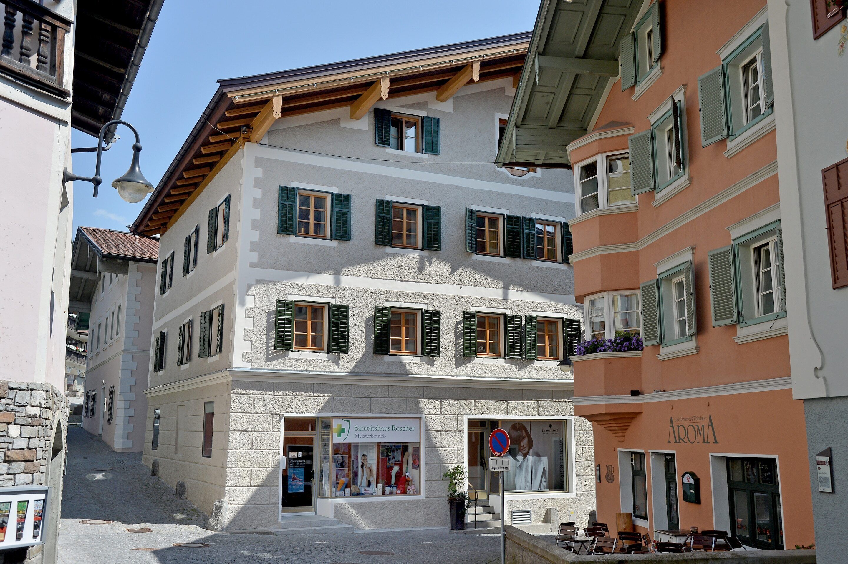 Un edificio con un ambulatorio al piano terra, un ristorante sulla destra e una strada stretta davanti.