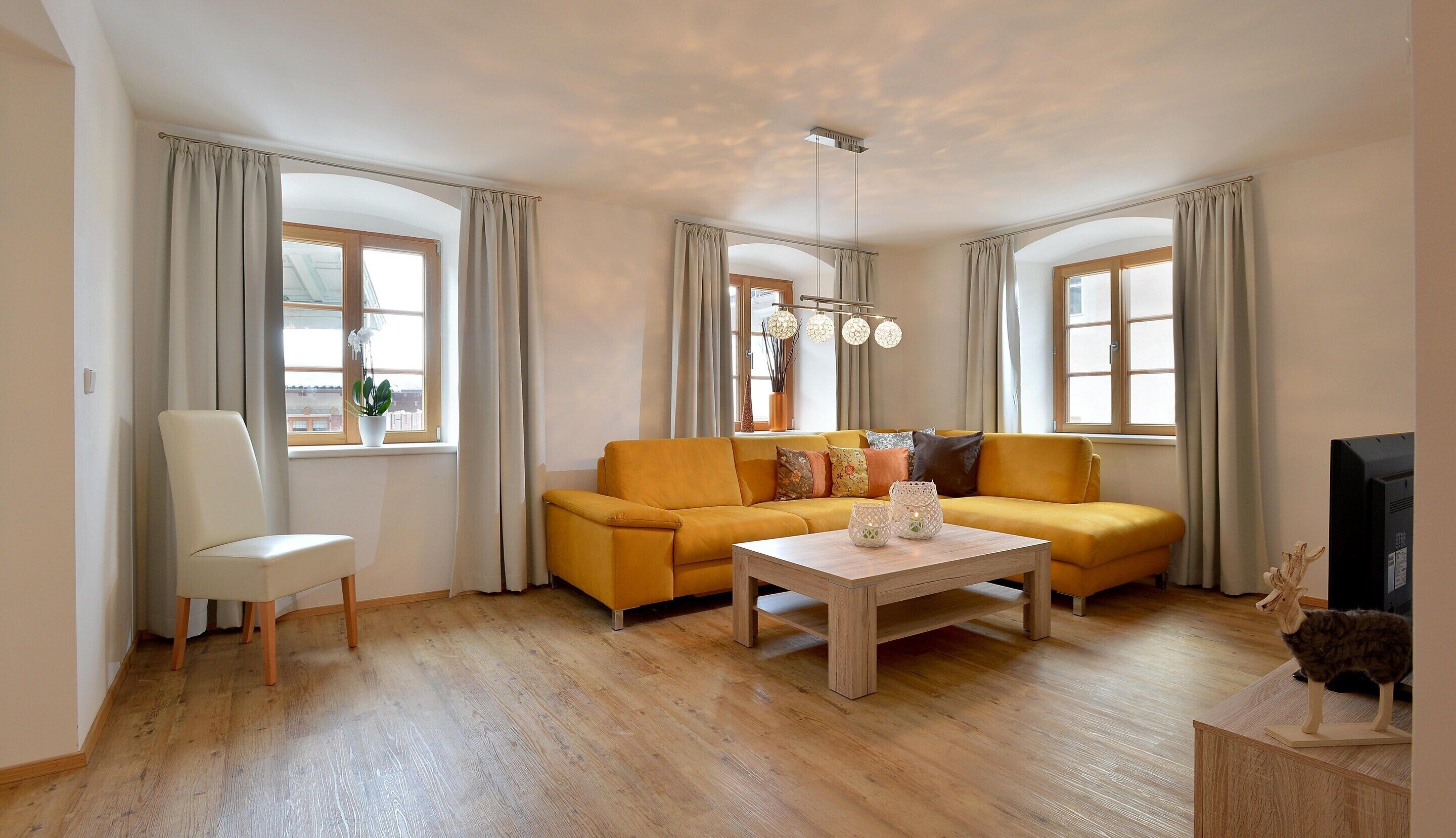 Een woonkamer met een bank, een fauteuil, een salontafel en een televisie.