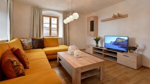 A modern living room with a sofa, coffee table, TV, and wooden cabinet. - Jagerhaus Apartment Near ski Area (Hopfgarten im Brixental)