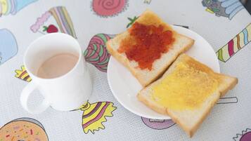 A white mug with a beverage on a table with a colorful tablecloth featuring various food illustrations.