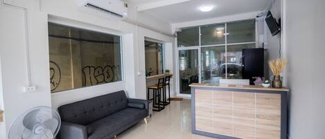 A modern living room with a grey sofa, a small table, and a TV mounted on the wall.