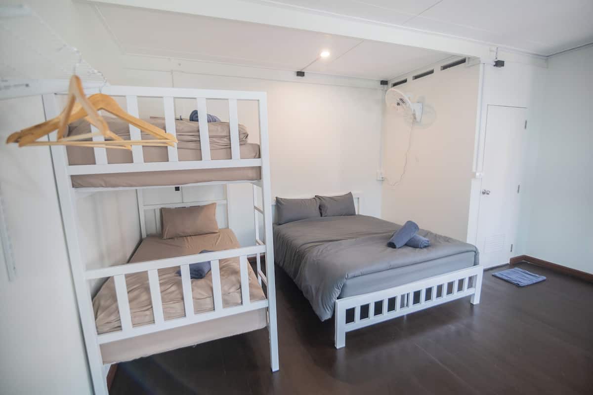 A bunk bed room with a white ceiling fan, a door, and a wooden hanger.