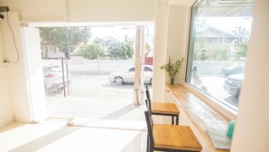 An interior view of a room with a large window, a wooden table, and a chair. - Bangkok Cozy Home at Khaosan Road (Bangkok)