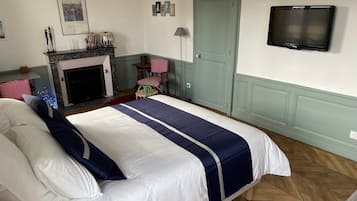 A bedroom with a bed, a television, a fireplace, and a door.