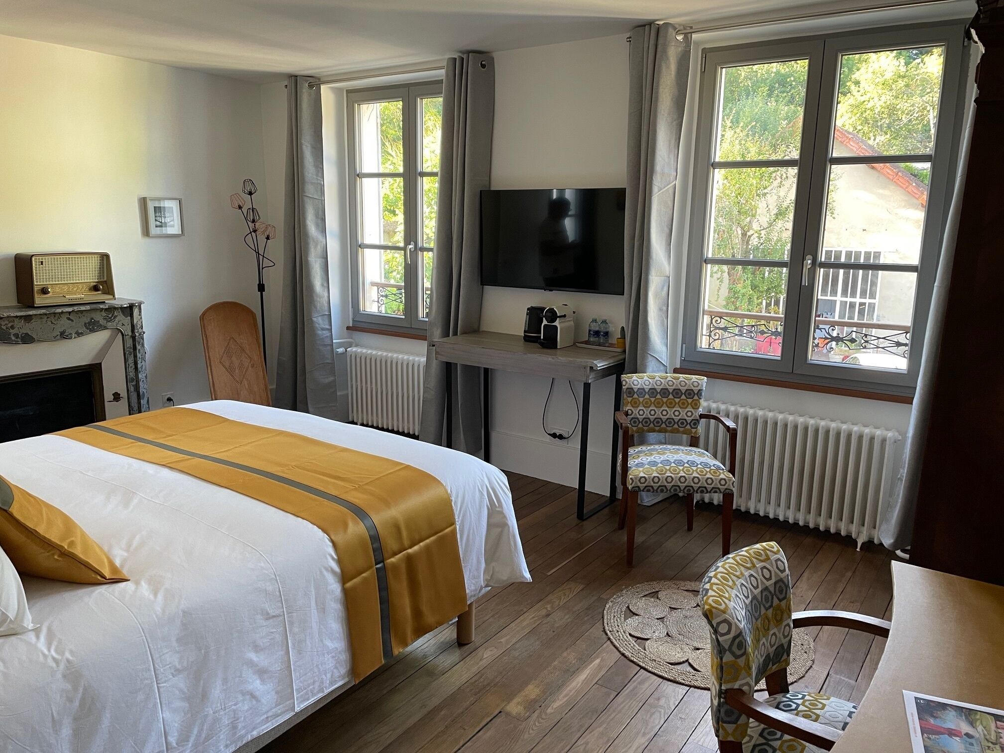Habitación de hotel con cama, escritorio con televisor, una silla y vista al exterior.
