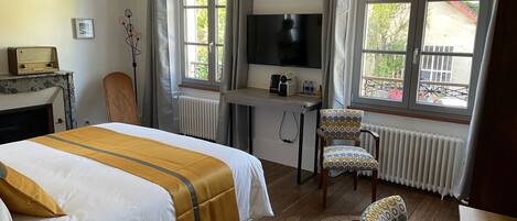 Habitación de hotel con cama, escritorio con televisor, una silla y vista al exterior.