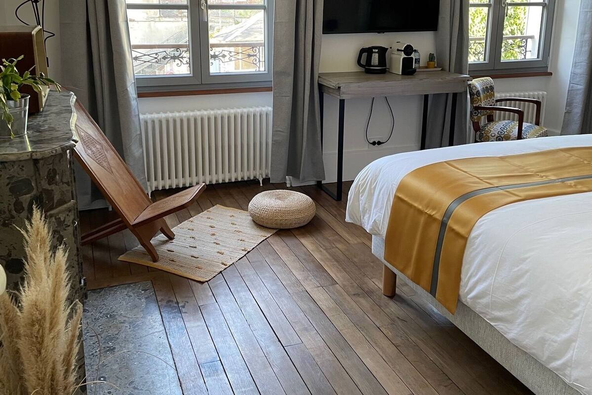 Une chambre avec un lit, une télévision, un bureau avec une bouilloire et une fenêtre avec des rideaux.