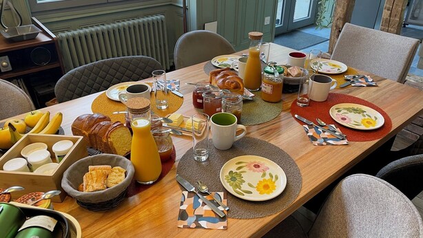 Een ontbijttafel gedekt met diverse etenswaren, bestek en toevoegingen.