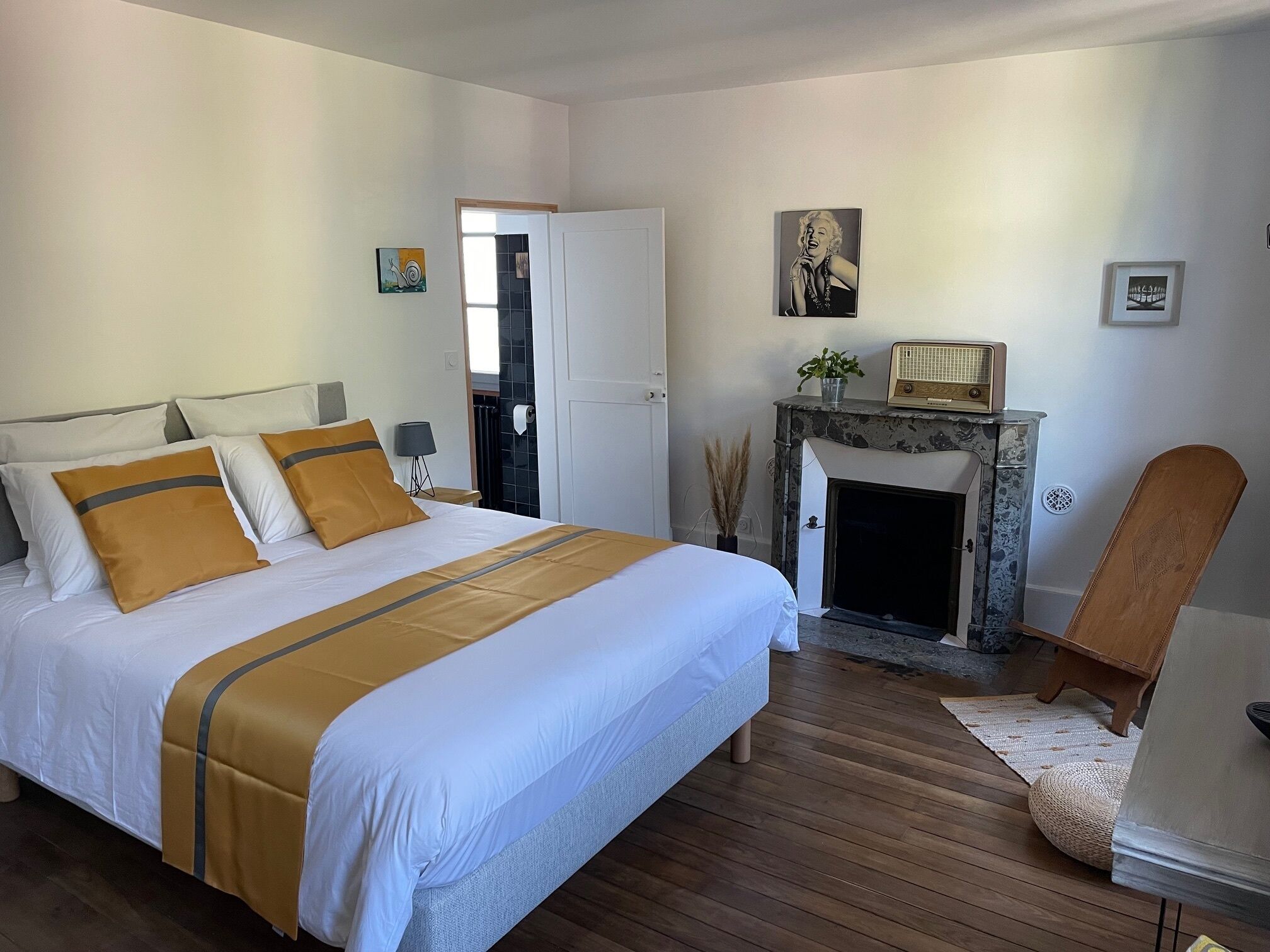 A bedroom with a large bed, a fireplace, and a chair.