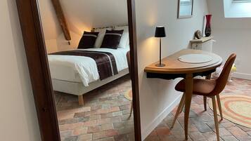 A bedroom with a bed, bedside table, lamp, and a small table with a chair.