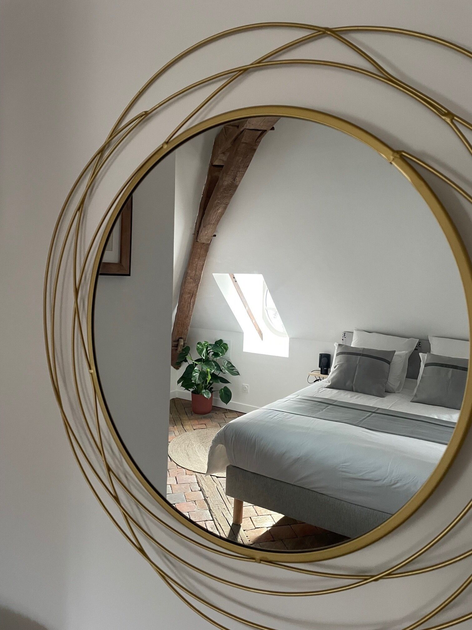 A bedroom with a bed, a potted plant, and a skylight.