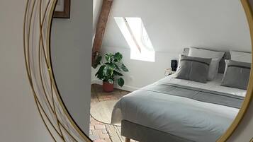 A bedroom with a bed, a potted plant, and a skylight.