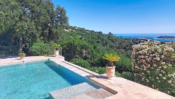 Une piscine avec vue sur la mer et les collines.