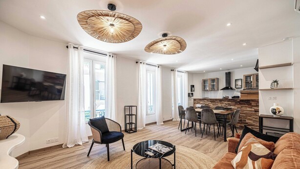 A modern living room with a TV, sofa, coffee table, and dining area.