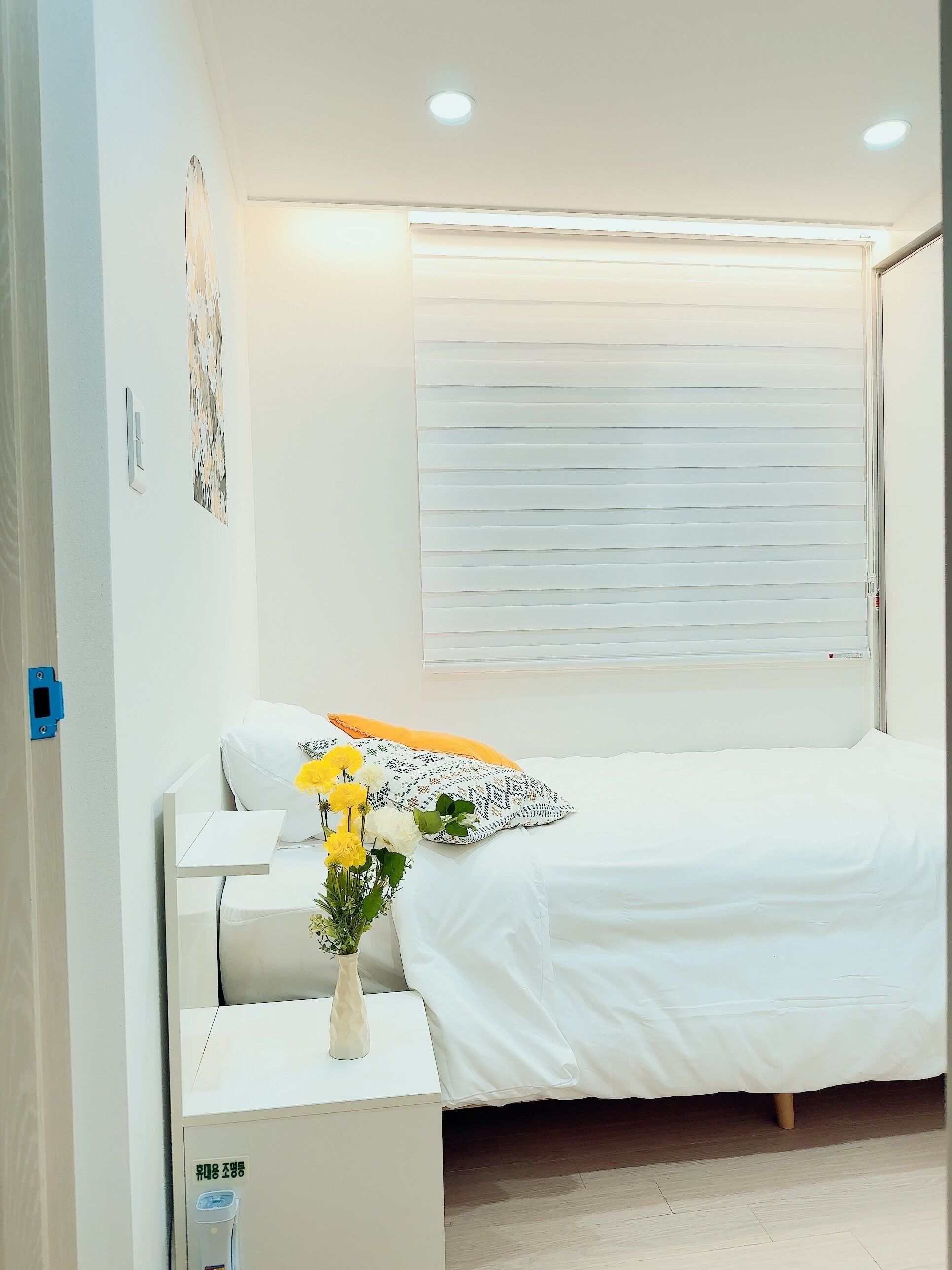 Une chambre à coucher moderne avec un lit, une table de chevet, une commode et une fenêtre avec des stores.