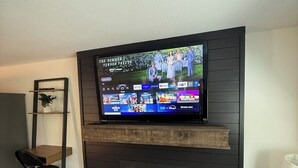 A living room with a flat-screen TV mounted on a dark wooden wall above a fireplace.