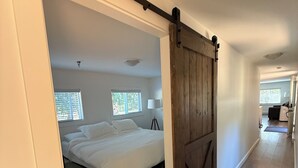 A bedroom with a bed, a laundry basket, and a wooden barn-style door.