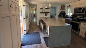 A modern kitchen with a central island, stainless steel appliances, and a wooden floor.