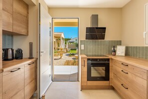 Een moderne keuken met houten kastjes, een ingebouwde oven en uitzicht op een terras.