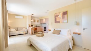 A modern hotel room with a large bed, a sofa, a dining area, and a kitchen. - Domus Olivea (Estézargues)