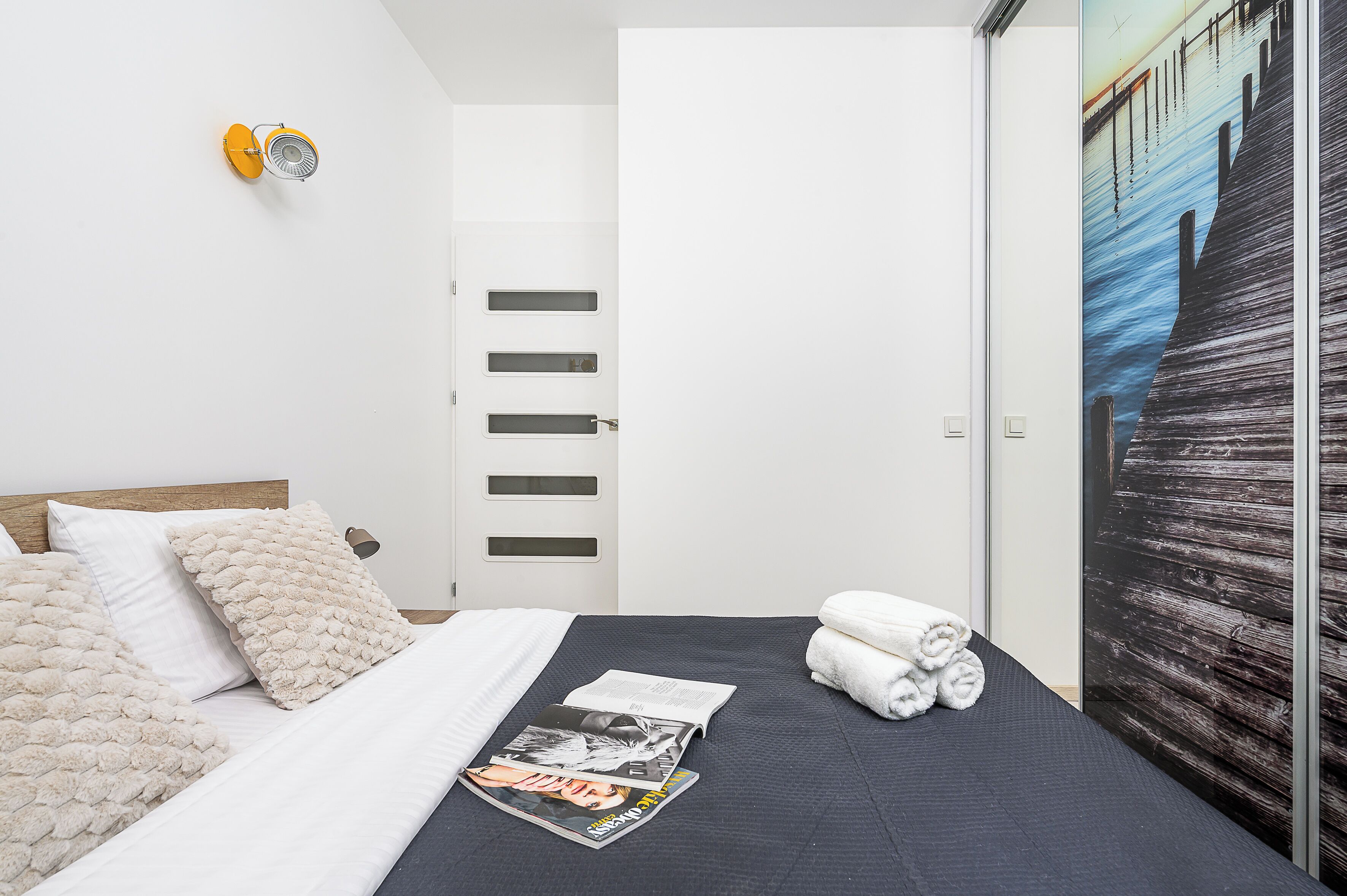 Une chambre à coucher avec un lit, des oreillers, un magazine et une serviette.